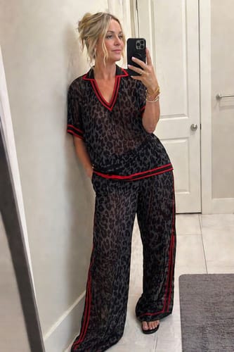 Reviewer wearing the loose leopard print blouse with red striped trim and matching pants.