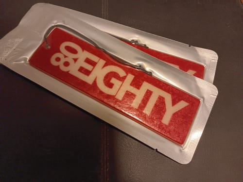 Reviewer's two red 80Eighty Smoke Ice Air Fresheners in their original packaging.