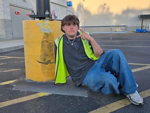 Reviewer sitting outside wearing the silver ARIES CHAIN with a grey polo shirt and yellow vest.