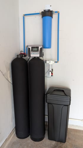 Customer's installed SoftPro® Elite HE Water Softener system with its black tanks and brine tank.