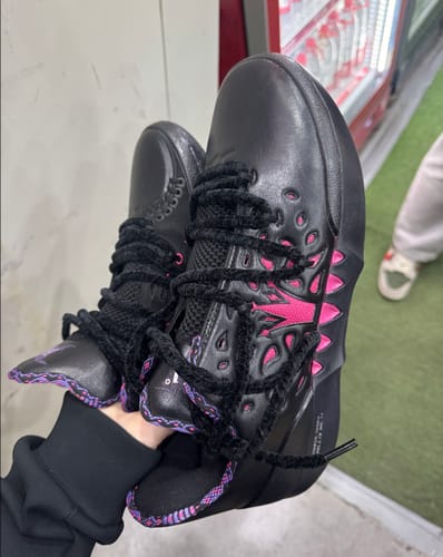 Customer holding a pair of black Joker 2 "Duality" shoes, showing the vibrant pink accents.