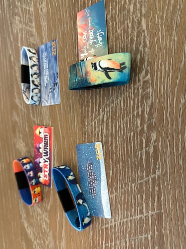 Reviewer's four bracelets and matching cards from the Penguin Pack laid out on a wooden surface.