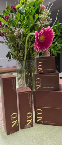 Reviewer's Crema cu Mucina de Melc and other products from the line arranged in front of a fresh flower bouquet.