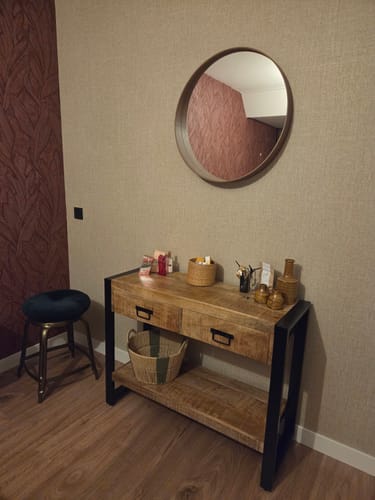 Recensent toont de mangohouten sidetable met zwart frame, opgesteld in een slaapkamer.