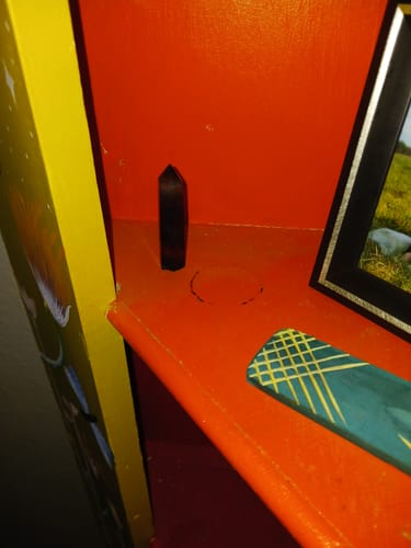 Customer's dark, pointed crystal from their VIP Crystal Club on an orange shelf.