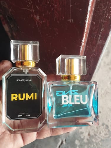 Reviewer holding the Rumi and Bleu De Zing perfume bottles in their hand.