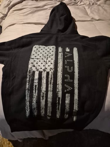 Reviewer's black Alpha Hoodie laid flat, showing the distressed American flag and 'ALPHA' graphic on the back.