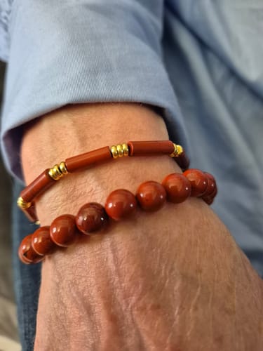 Une cliente porte le bracelet réglable en jaspe rouge à son poignet avec un autre bracelet.