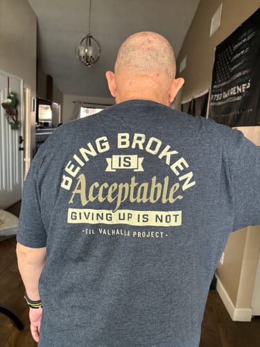 Reviewer from behind wearing the Being Broken t-shirt, showing the back print in a hallway.
