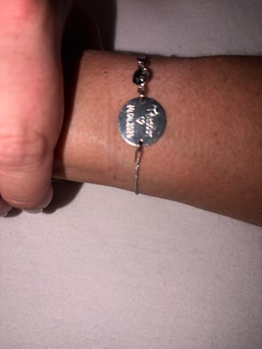 Rezensent trägt das Priority Express Armband mit runder, gravierter Plakette am Handgelenk.