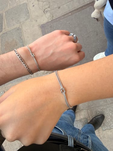 Customer showing matching silver-colored knot bracelets on two wrists outdoors.