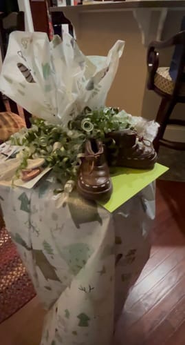 Reviewer's brown Nordic Baby Boots used as a decoration on top of a large, wrapped baby shower gift.