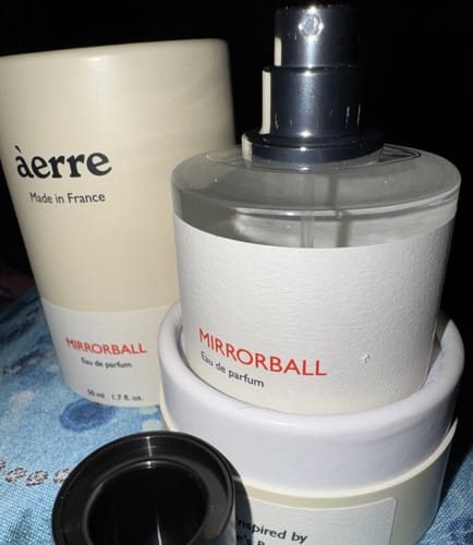 Customer's Mirrorball perfume bottle with the cap off, displayed next to its white cylindrical packaging.