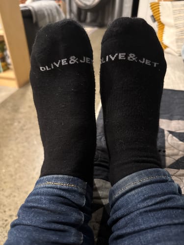 Customer relaxing with their feet up while wearing the black Quarter Socks indoors.