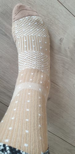 Anmelder viser den mønstrede, beige støttestrømpe på foden.