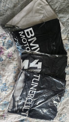 Reviewer's four MYSTERY TEEs in their clear packaging, showing the different black and white shirt designs received.