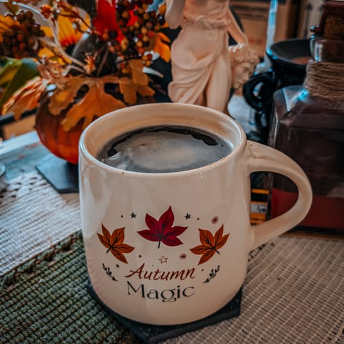Kundenfoto der 'Autumn Magic'-Tasse, gefüllt mit Kaffee, auf einem Tisch mit herbstlicher Dekoration.