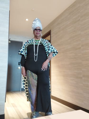 Reviewer wearing the patterned Kimono Cover Up over a black jumpsuit in a hallway.
