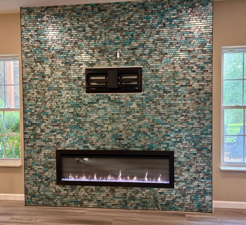 Customer's SimpliFire Allusion Slim fireplace recessed into a decorative teal tile wall, showing active flames.