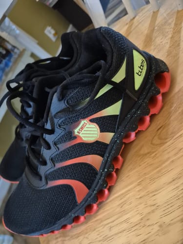 Customer's pair of black TUBES 200 trainers with red soles and green accents, seen from the side.
