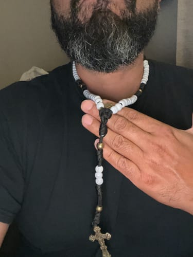 Reviewer wearing and holding the Matte White Crackle Beads Rosary against their chest.