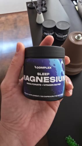 Customer holding the black jar of Complex Sleep Magnesium supplement in their hand.