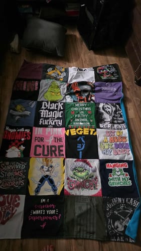 Customer's completed Project Repat T-Shirt Quilt made from various graphic tees, displayed on a wooden floor.