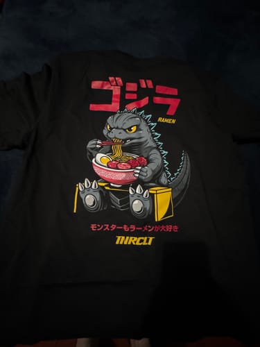 Customer's black RAMEN MONSTER TEE laid out, showing the back graphic of a monster eating ramen.