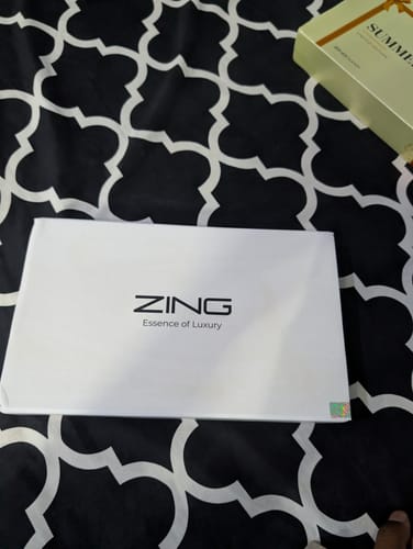 Customer's white 'Zing' packaging for the Summer Box, lying on a black and white patterned surface.