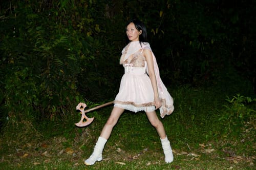 Reviewer models the pink Bambi Princess Fur Chiffon Dress with lace shorts in a wooded area at night, showing its short fit.