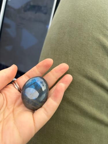 Customer holding a polished labradorite moonstone crystal in the palm of their hand.