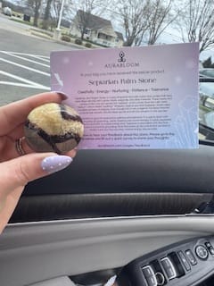 Customer holding a round Septarian Palm Stone from their monthly crystal subscription box with its info card.