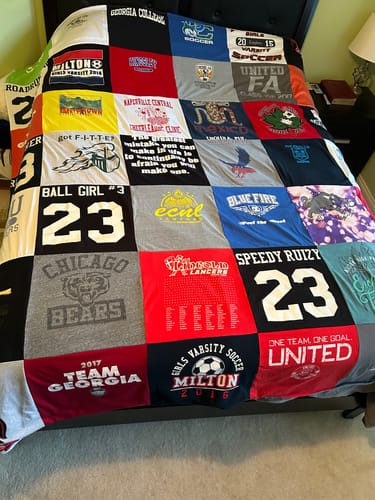 Customer's colorful Premium T Shirt Quilt, made from many different t-shirts, spread across a bed.