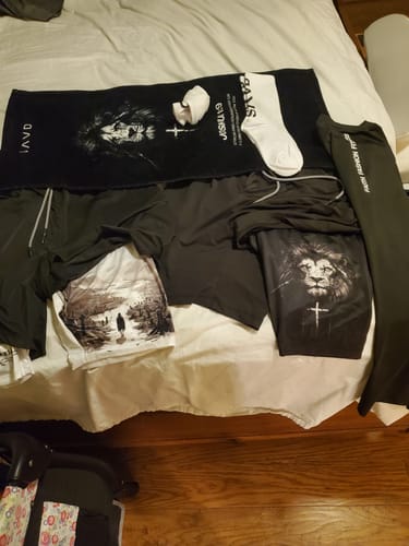 Reviewer's black training towel and white socks laid out with other matching apparel on a bed.
