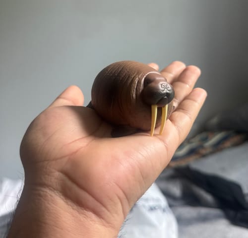 Customer holding the hefty, brown walrus figure from the Laugh And Grow Fat blind box in their palm.