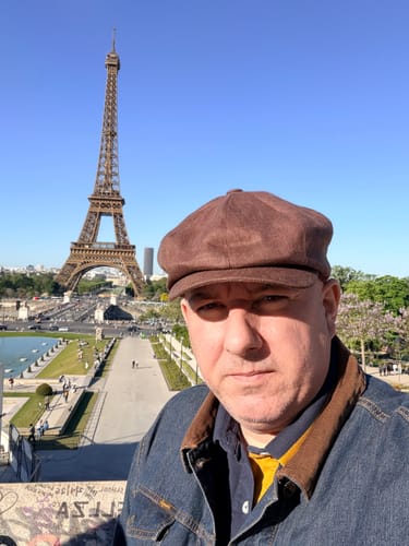 Customer wearing a brown JP Cap Linen with the Eiffel Tower in the background.