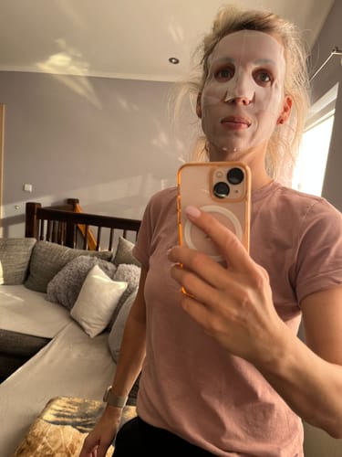 Eine Kundin macht ein Selfie, während sie die Kollagen Boosting Maske trägt.