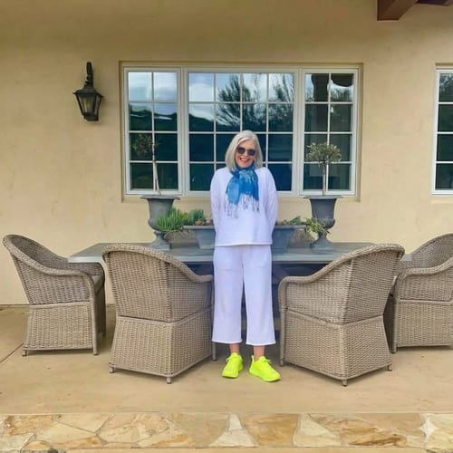 Reviewer standing outdoors wearing bright yellow Ortho Balance shoes with a casual white outfit.