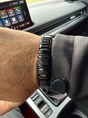 Close-up of a customer wearing the personalized black bracelet with engraved name beads.
