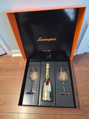 Customer's Lamborghini Oro Vino Spumante gift set in its open box, showing the wine bottle and two crystal glasses.