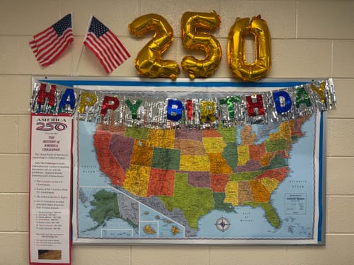 Reviewer's classroom display for the "250 History Challenge," with a U.S. map, flags, and "250" balloons.