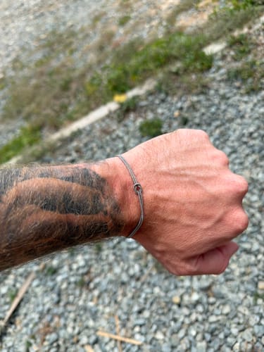 Reviewer wearing the subtle Forever Knot Bracelet on their tattooed wrist.