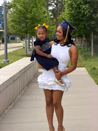 Customer holding a child wearing the navy smocked dress for graduation pictures.