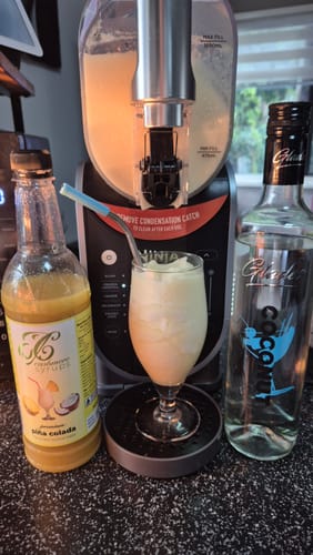 Customer's Piña Colada Cocktail Mix next to a slushie machine and a glass of the finished frozen drink.