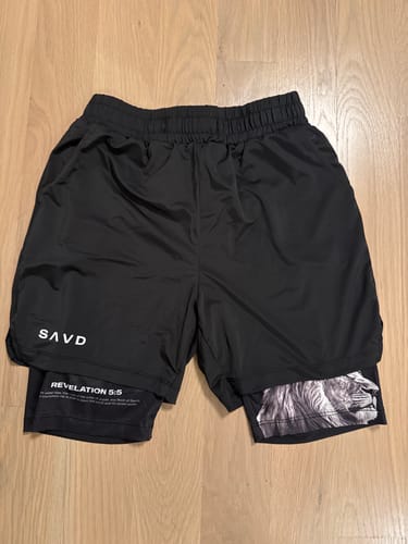 Customer's black 'Lion' Youth Performance Shorts with Revelation 5:5 text and a lion graphic on the inner layer.