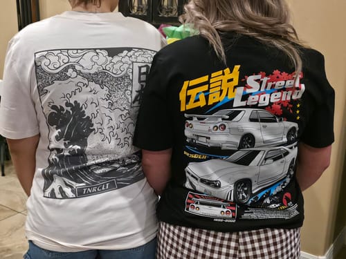 Reviewer standing next to another person, showing the back graphic of the black STREET LEGEND TEE.