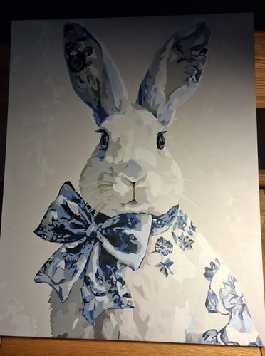 Customer's completed Delft Blue Bunny paint by number, showing the finished portrait of a rabbit with a large blue patterned bow.