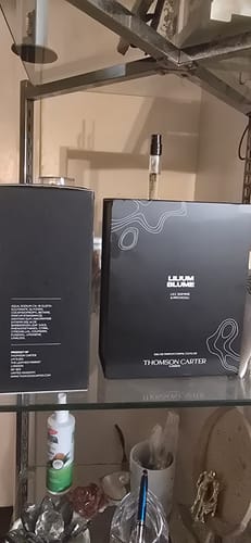 Customer's black Lilium Blume perfume box and sample vial displayed together on a glass shelf.