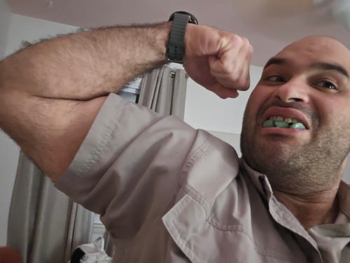 Reviewer flexing their bicep while showing the green Kratos Kreatine gummies in their mouth.