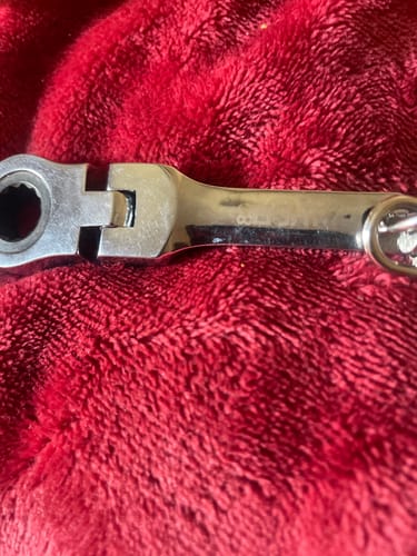 Customer's silver 10mm wrench keychain resting on a plush red surface.